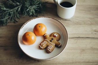 A festive scene with a gingerbread man cookie, coffee and fresh oranges on a rustic plate, set