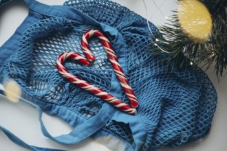 A vibrant blue string bag lays on a white surface, gently cradling two candy canes formed into a