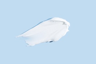 Smooth texture of a white cream or gel smear, isolated on a serene blue background, representing