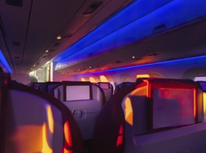 Interior view of an airplane cabin aglow with vibrant mood lighting, showcasing the comfortable