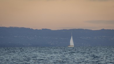 A serene scene of a sailboat gracefully moving across a calm lake in Geneva, set against a backdrop