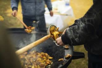 Cropped unrecognizable staff cooking potatoes at a bustling street food fair, enhancing the aroma