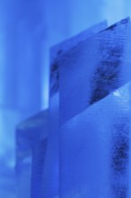 Close-up of intricately shaped ice structures illuminated with a cool blue glow at a temporary ice