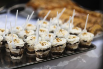 A tray of delicious layered dessert cups, each topped with whipped cream and crunch, beautifully
