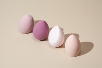 A row of pastel cosmetic sponges in various soft tones on a neutral backdrop, showcasing their
