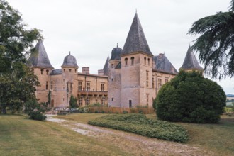 A charming Chateau Caumont castle medieval with tall turrets sits amidst lush greenery and a scenic
