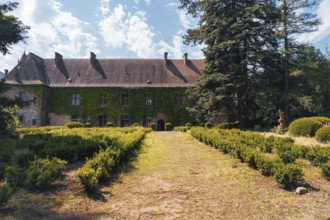 A stunning view of Chateau Polignac in France, surrounded by lush greenery and a neatly lined
