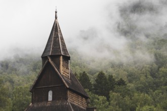 Discover the serene beauty of an ancient Norwegian stave church set against a mist-covered forest