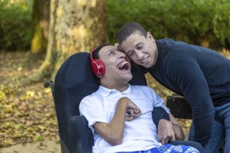 Heartwarming image of Spanish Cameroonian siblings outdoors, one in a wheelchair with cerebral