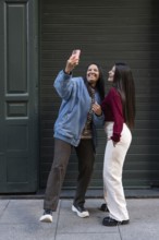 A joyful latin lesbian couple poses for a selfie in an urban setting, showcasing their unity and