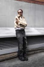 A woman confidently poses in a trendy fur jacket and sunglasses, embodying urban street style.