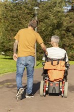 A thoughtful moment capturing a person walking with a friend in a wheelchair with a cerebral palsy