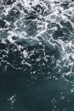 Moving seawater with white foam and dynamic texture. Waves and bubbles create a natural and