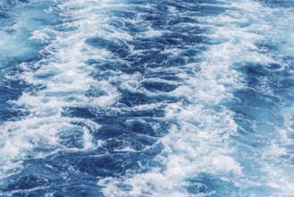 Turbulent sea waves with foam and ripples in deep blue water. The movement captures the raw power