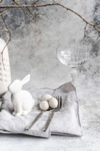 An elegant Easter-themed display featuring a white ceramic rabbit, three speckled eggs, and a clear