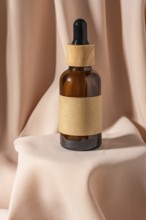 A stylish amber glass dropper bottle with a wooden cap rests gracefully on soft beige fabric
