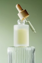 An elegant serum dropper bottle with a pipette resting on its rim, filled with a milky serum, set