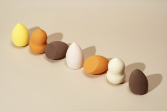 A row of cosmetic sponges in vibrant shades of yellow, orange, and brown displayed on a neutral