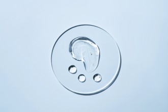 Transparent liquid droplets rest on a smooth, light surface The image showcases the purity and