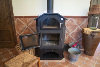 A traditional wood burning stove with its door open, situated in a cozy room corner showing warm,