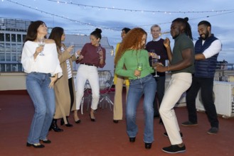 A lively group of friends celebrating on a rooftop, enjoying music and drinks They dance and laugh