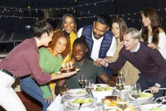 A joyful group of friends gathered at a vibrant outdoor birthday party, enjoying food and wine