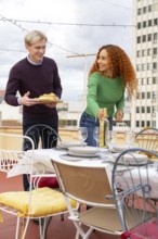 Two friends preparing to celebrate an outdoor party on a rooftop They share drinks and snacks,