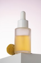 Elegantly displayed cosmetic serum bottle with a dropper, positioned on a geometric podium against