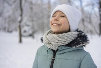 A young girl stands amidst a snowy landscape, wearing a warm scarf and hat, radiating happiness.