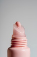Close-up view of a pink lip balm on pink tube against a neutral background. This image showcases