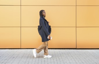 A young African American businesswoman with braids, dressed in a formal grey jacket and beige