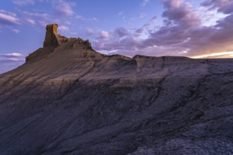 A mesmerizing view of a rock formation in Utah highlighted by the soft glow of a sunset, featuring