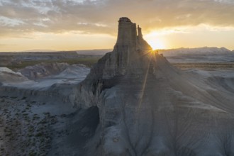 Breathtaking view as the sun sets behind a rugged peak in Utah, casting soft light over layered