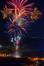 Vibrant fireworks illuminate the night sky above the Ebro River, casting colorful reflections on