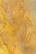 This image captures the detailed texture of golden mud, showcasing various tones and intricate
