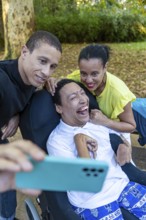 Two siblings pose for a joyful selfie with their disabled brother, who has cerebral palsy, enjoying
