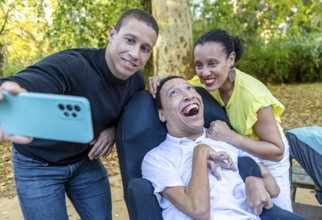 Two siblings pose for a joyful selfie with their disabled brother, who has cerebral palsy, enjoying