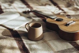 A warm and peaceful morning scene featuring a ukulele, a coffee mug, and an open notebook resting