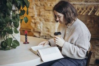A young woman enjoys reading a book in a cozy bookstore setting She is sipping coffee, surrounded