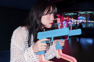 An Asian Gen Z girl fully immersed in the vibrant atmosphere of an arcade She is playing a game