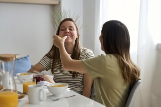 A lesbian couple enjoys a joyful breakfast together, sharing smiles and affection This heartwarming