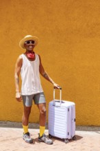 LGBTQIA+ man stands joyfully beside a suitcase, dressed vibrantly and ready for a holiday. A