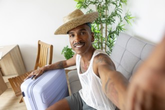 A cheerful LGBTQIA+ individual with a suitcase, ready for holiday adventures. Wearing a straw hat