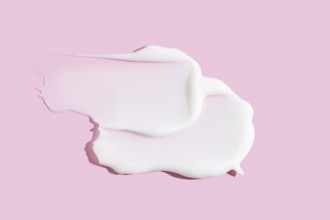 A delicate smear of creamy cosmetic product, displaying texture against a soothing pink background.