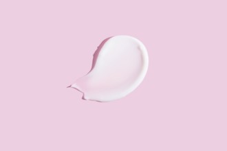 A high-quality image featuring a dollop of cosmetic cream smeared on a pastel pink background,