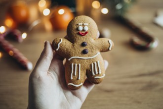 A hand holds a charming gingerbread man cookie decorated with icing Soft lighting and blurred