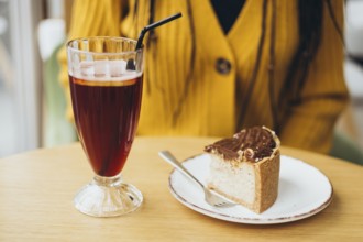 A cozy cafe scene with a refreshing iced coffee in a tall glass and a delectable slice of chocolate