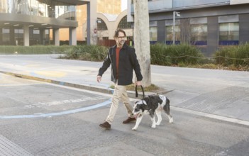 A man walks his dog through a busy city intersection, showcasing urban life and pet companionship
