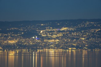 A captivating nighttime view of Lausanne, Switzerland, with the city lights reflecting on the calm