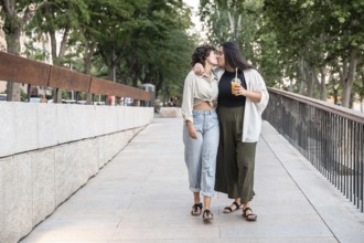 A lesbian couple shares a tender kiss while walking down a city street, displaying affection and